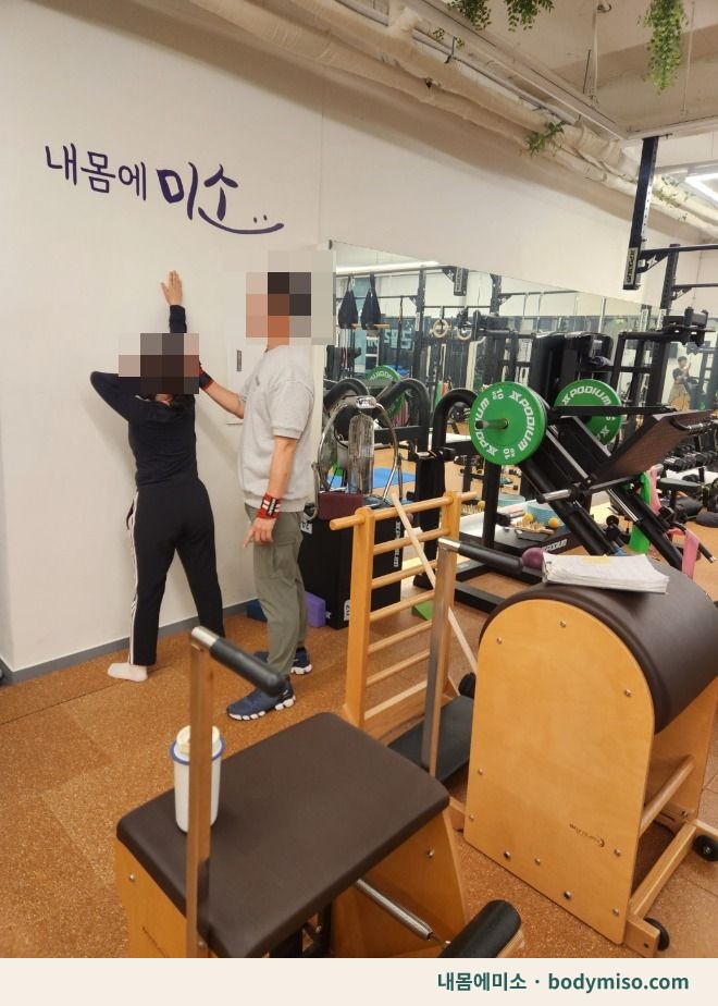필라테스 센터에서 강사가 여성 회원의 운동 자세를 지도하고 있는 모습